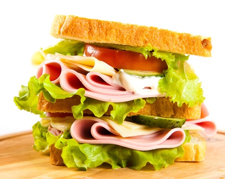 big sandwich with fresh vegetables on wooden board on white backgroundの写真素材