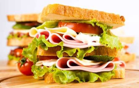 big sandwich with fresh vegetables on wooden boardの写真素材