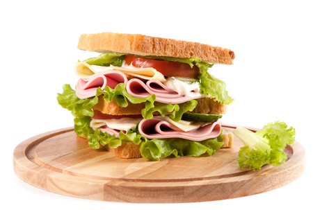big sandwich with fresh vegetables on wooden board on white の写真素材