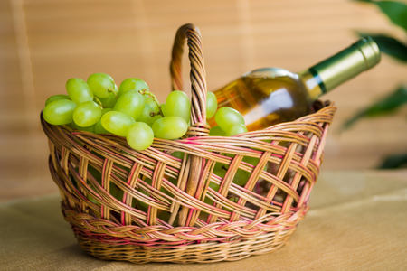 bunch of grapes and white wine bottle in the basketの写真素材