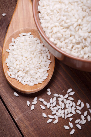 white rice in a  bowl and wooden spoonの写真素材