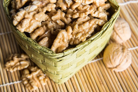 Walnuts in wicker basket on light  backgroundの写真素材