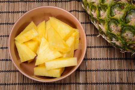 ripe pineapple cut into slices in the bowlの写真素材