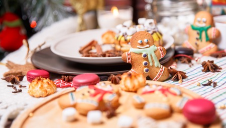 colorful Christmas sweets and hot drinks on the holiday table near the Christmas tree