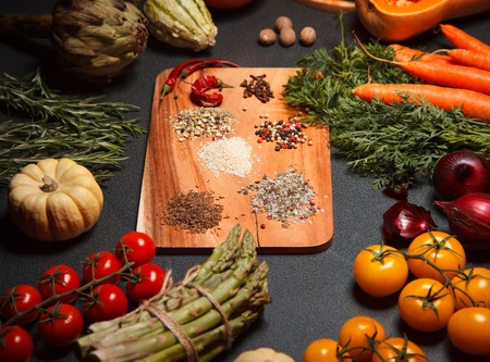 an abundance of vegetables and spices closeup on wooden table tomatoes, pumpkins, carrot, onion, pepper and otherの写真素材