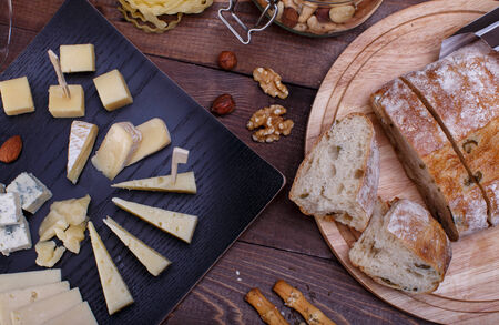 elegant appetizer with white wine different cheeses, bread and pasta on a wooden table