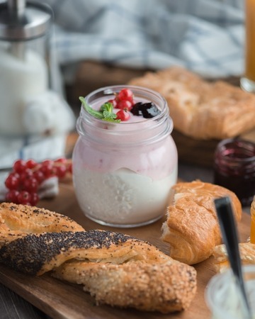 red currant berry mousse in the little jar and the  buns around on a wooden tableの写真素材