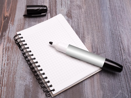 black marker and cap and two sheets torn from a notebook on a wooden backgroundの写真素材