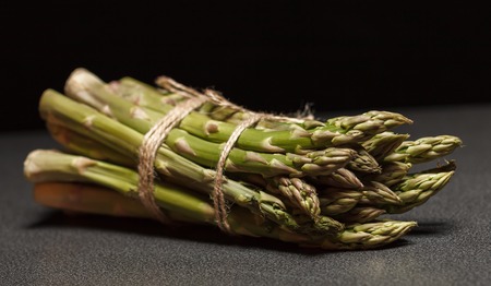 Bunch of green asparagus on black backgroundの写真素材