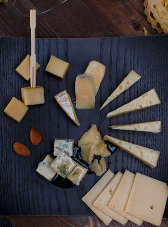 elegant appetizer with white wine different cheeses, bread and pasta on a wooden tableの写真素材