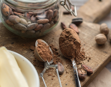 spoon with cocoa powder and raw cocoa beans on the wooden boardの写真素材