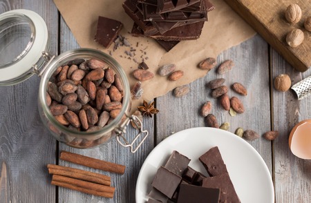 cocoa beans, spices and pieces of chocolate on the wooden tableの写真素材