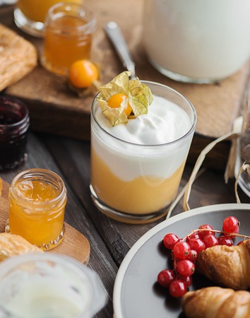 croissants with the red currant on the brown plate near cream mousse and other foor for breakfastの写真素材