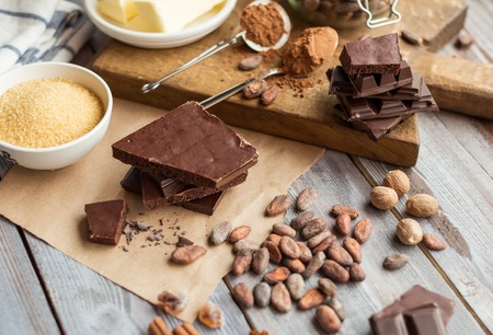 glass of milk, fresh butter, cocoa powder and beans, pieces of cocolate and spices on the wooden tableの写真素材