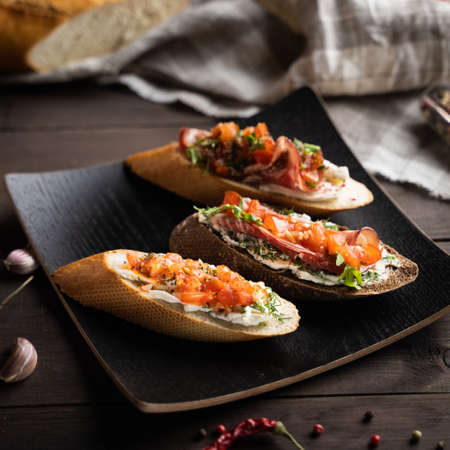 From above yummy bruschettas placed on square plate near napkin and spices in kitchenの写真素材