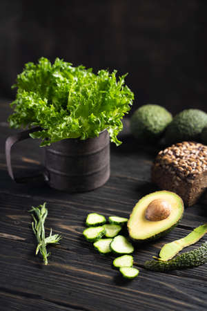 Fresh green vegetables and loaf of rye bread placed on wooden rustic table