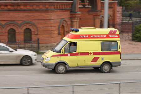 Yellow ambulance truck racing down the street against the background of Alexander Nevsky Cathedral...