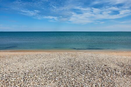 Background of sea of Azov with blue sky, white clouds and deserted sea shells beach. Copy space.の写真素材