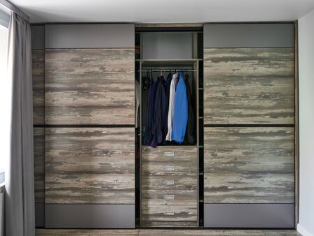 Modern wardrobe with open sliding doors and drawers in room.の写真素材