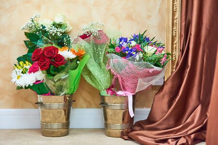 Presented bouquets of flowers on wedding ceremony or other festive event in two metal buckets stand on floor against wall.の写真素材