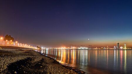 Beautiful night view from Sea Beach to Illuminated cityscape. Reflections of lights in Black Sea in Batumi, Adjara, Georgia.の写真素材