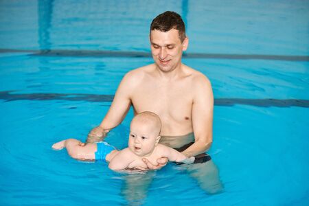 Father teaching little baby to swim in water pool. Swimming lessons for children. Healthy Family Life. Responsible parenting concept.の写真素材