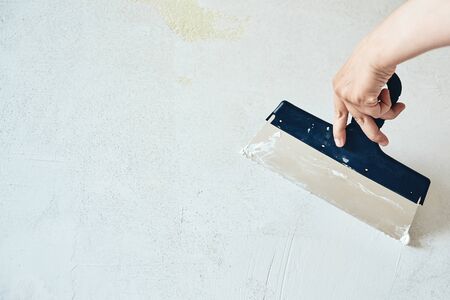 Spatula with putty in hand. Worker puts of plaster on wall. Repair work, decoration building concept, construction.の写真素材