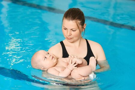Mother teaching little baby to swim in water pool. Swimming lessons for children. Healthy Family Life.の写真素材