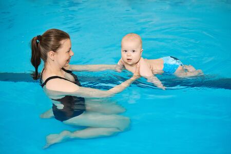 Mother teaching little baby to swim in water pool. Swimming lessons for children. Healthy Family Life.の写真素材
