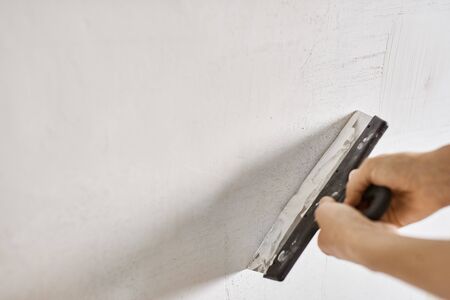 Spatula with putty in hands. Worker puts of plaster on wall. Repair work, decoration building concept, construction.の写真素材