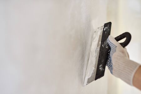 Spatula with putty in hand. Worker puts of plaster on wall. Repair work, decoration building concept, construction.の写真素材
