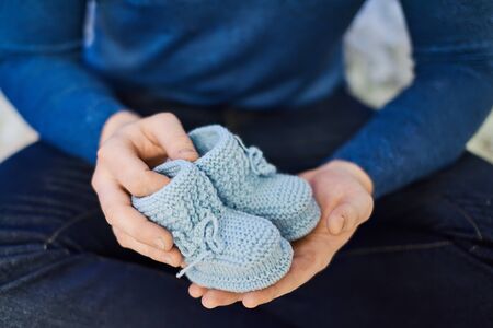 Male ready to become father holds blue little booties for his unborn baby. Family concept.の写真素材