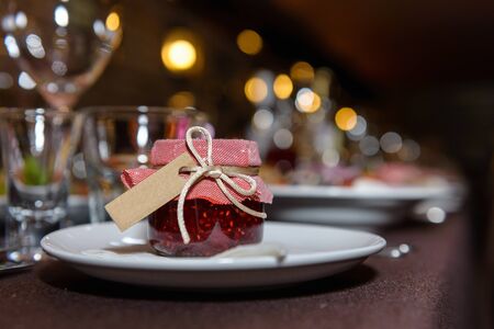 Jam from red raspberries, prepared by hand, is on the table in beautiful little jar under the lid.の写真素材