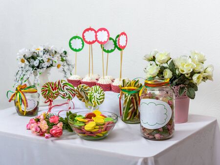 Sweet table standing on white background with sweets, lollipops, macaroni, marshmallows for children holiday or wedding.の写真素材