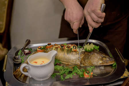 Zander cooked on the grill with herbs and vegetables cook cuts with knife.の写真素材