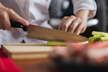 Female chef cutting cucumber on a wooden boardの写真素材