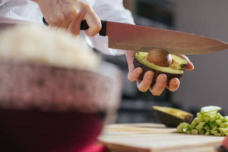 Female chef cutting avocado in a home kitchen