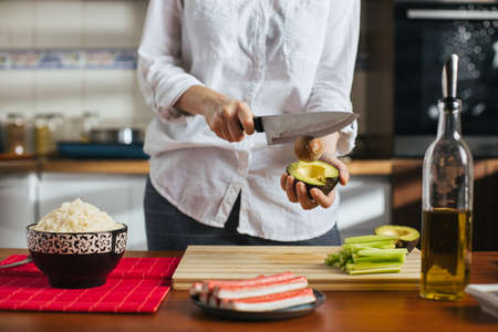 Female chef cutting avocado in a home kitchenの写真素材
