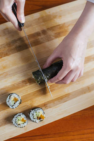 Female chef cutting sushi in the kitchenの写真素材