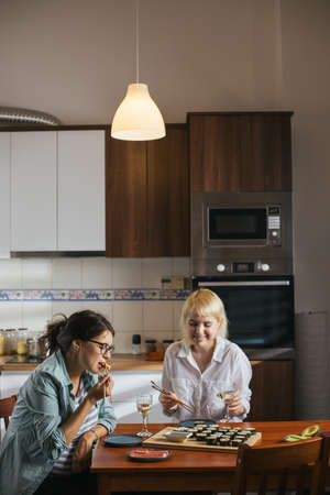 Two friends eating sushi for dinner at home