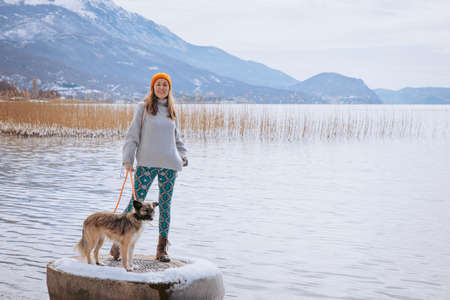 Woman walking her dog on a lake shore in winter
