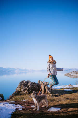 Woman walking her dog on a lake shore in winterの写真素材