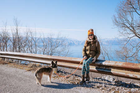 Woman walking her dog with lake in the backgroundの写真素材