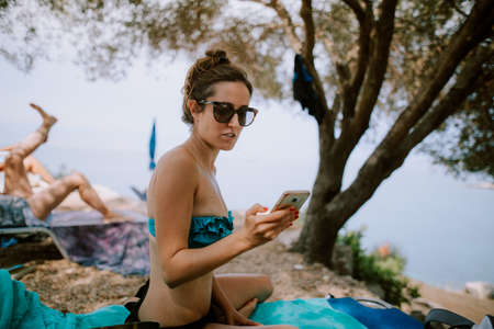 Woman using smartphone at the beachの写真素材