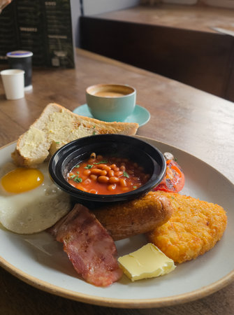 Full English breakfast with beans and sausage served on wooden tableの写真素材