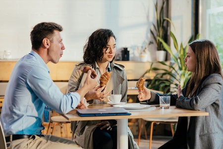 Coworkers enjoying coffee break with croissants and conversation