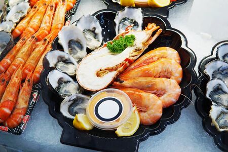 Seafood plate set on ice selling at market. Close up detail on small seafood platter with fresh prawn, oyster and dipping sauce. Selective focus of seafood plate ready for sell at market.の写真素材