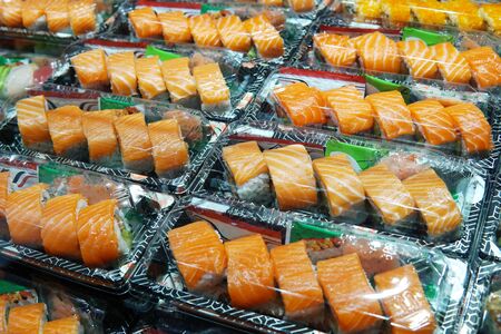 Selective focus on salmon sushi box. Salmon sushi in takeaway box ready for sale in restaurant. Sushi box with wasabi and ginger for hurry meal. Salmon sushi box cook in asian styleの写真素材