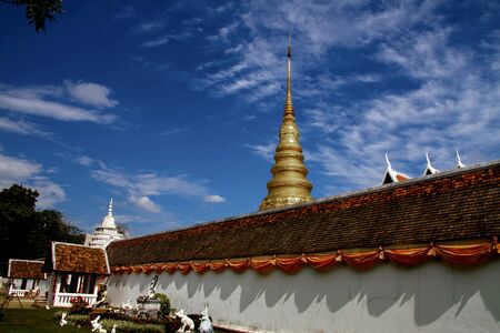 Brick wall and gold pagoda with white cloud at Wat Phra That Chae Haeng, Nan province, Thailand の写真素材
