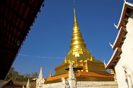 Gold pagoda among shurch with  sky at Wat Phra That Chae Haeng, Nan province, Thailandの写真素材